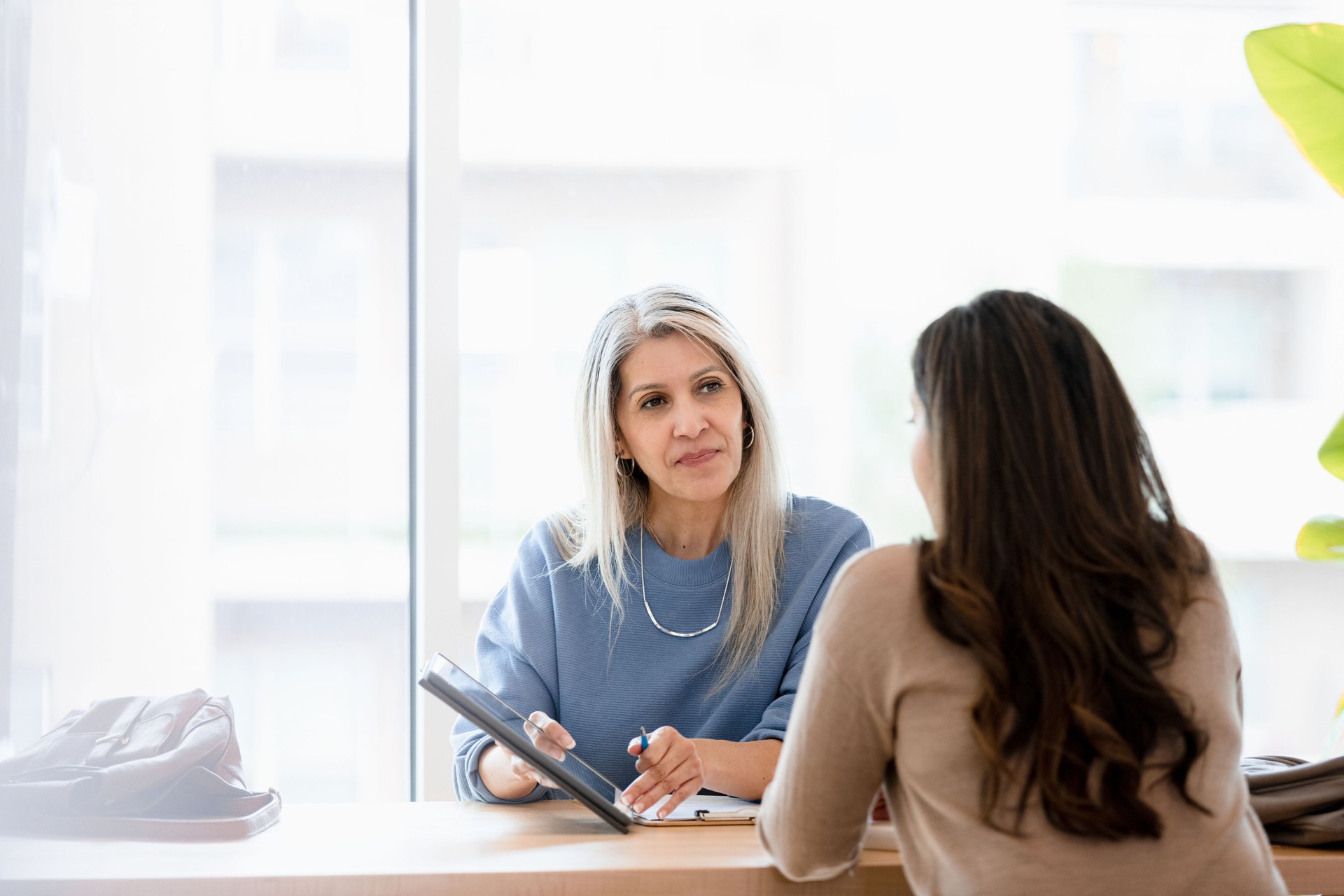 Serious mid adult female lawyer listens to unrecognizable female client